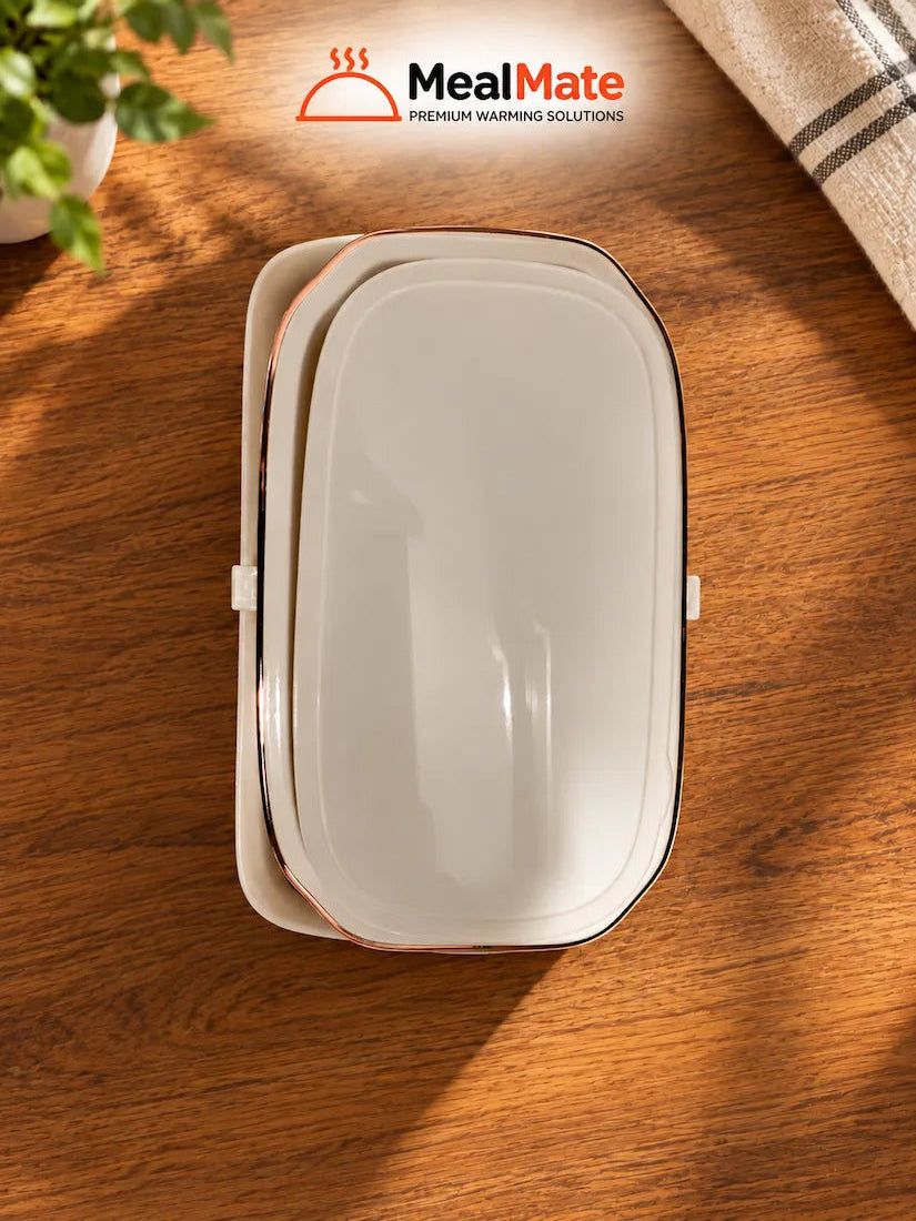 A white rectangular warning label with rounded corners and a black border sits on a wooden tabletop. The MealMate brand logo is printed at the top of the label.